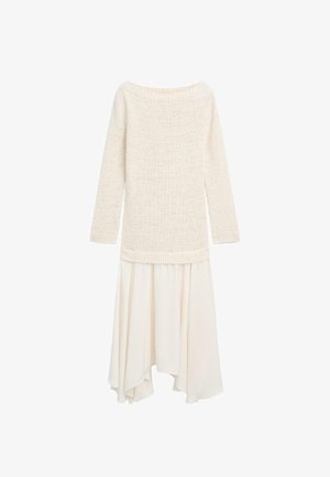 Roomkleurige, lange mouwen gebreide trui gecombineerd met een vloeiende, asymmetrische roomkleurige rok tegen een witte achtergrond.