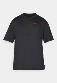 Czarna koszulka z krótkim rękawem, okrągłym dekoltem i czerwonym logo "ATLETI" z suwakiem Nike. Miękki, gładki materiał, regularny krój, minimalistyczny design.