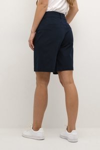 Navy blue shorts with a tailored fit, featuring a flat waistband, two back pockets, and worn with white sneakers.