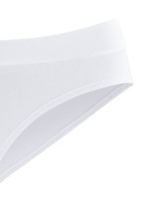 Completi in cotone bianco con una texture liscia, dotati di un ampio elastico in vita e un design semplice e senza cuciture.