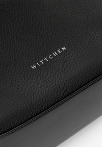 Czarna skórzana torba o teksturowanym wykończeniu, z logo "WITTCHEN" w kolorze srebrnym. Gładkie akcenty kontrastują z wypukłą teksturą materiału.