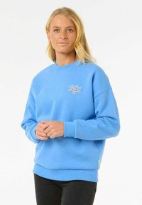 Sudadera de un azul claro con cuello redondo, puños acanalados y detalle de logotipo bordado. La tela parece suave y ligeramente texturizada.