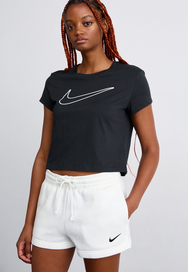 Camiseta corta negra con el logo blanco de Nike, combinada con pantalones cortos de sudadera blancos que presentan un pequeño logo negro. Material de algodón, corte relajado.