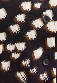 Czarna tkanina z brązowym i kremowym abstrakcyjnym wzorem pociągnięcia pędzla, z czarnymi guzikami i gładką teksturą.