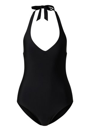 Kobieta w czarnym jednoczęściowym kostiumie kąpielowym, dużym luźnym czarno-białym pareo tie-dye, czarnych klapkach i odbijających futurystycznych okularach przeciwsłonecznych.