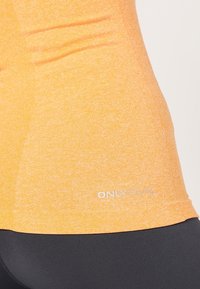 Débardeur melange orange en tissu doux et extensible. Présente un col arrondi et un petit logo "ONLY" en argent près du bas.