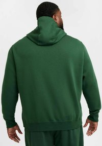 Grön hoodie i mjukt tyg, med snörning i huvan, ribbade ärmslut och nederkant. Enkel design utan synliga mönster eller logotyper.