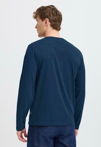Marineblaues Langarm-T-Shirt aus weicher Baumwolle mit einem Rundhalsausschnitt, geradem Saum und einer lockeren Passform. Minimalistisches Design ohne Muster.