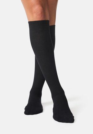 Schwarze Kniestrümpfe aus Rippgewebe; glatte Textur und figurbetontes Design. Keine sichtbaren Muster oder Akzente.