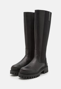 Botas negras de cuero y textil hasta la rodilla, con una suela de goma gruesa y detalles en panel lateral. Acabado suave y diseño elegante.