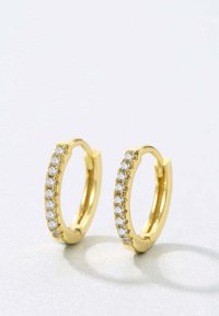 Pendientes de aro de oro que presentan una fila de pequeñas piedras de strass transparentes en la parte frontal. Acabado liso y brillante con forma redondeada y diseño minimalista.