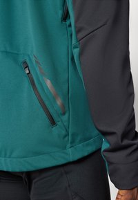 Türkise und schwarze Jacke mit einer seitlichen Reißverschlusstasche, glattem Textilgewebe und kontrastierenden Farbpanelen an den Ärmeln.