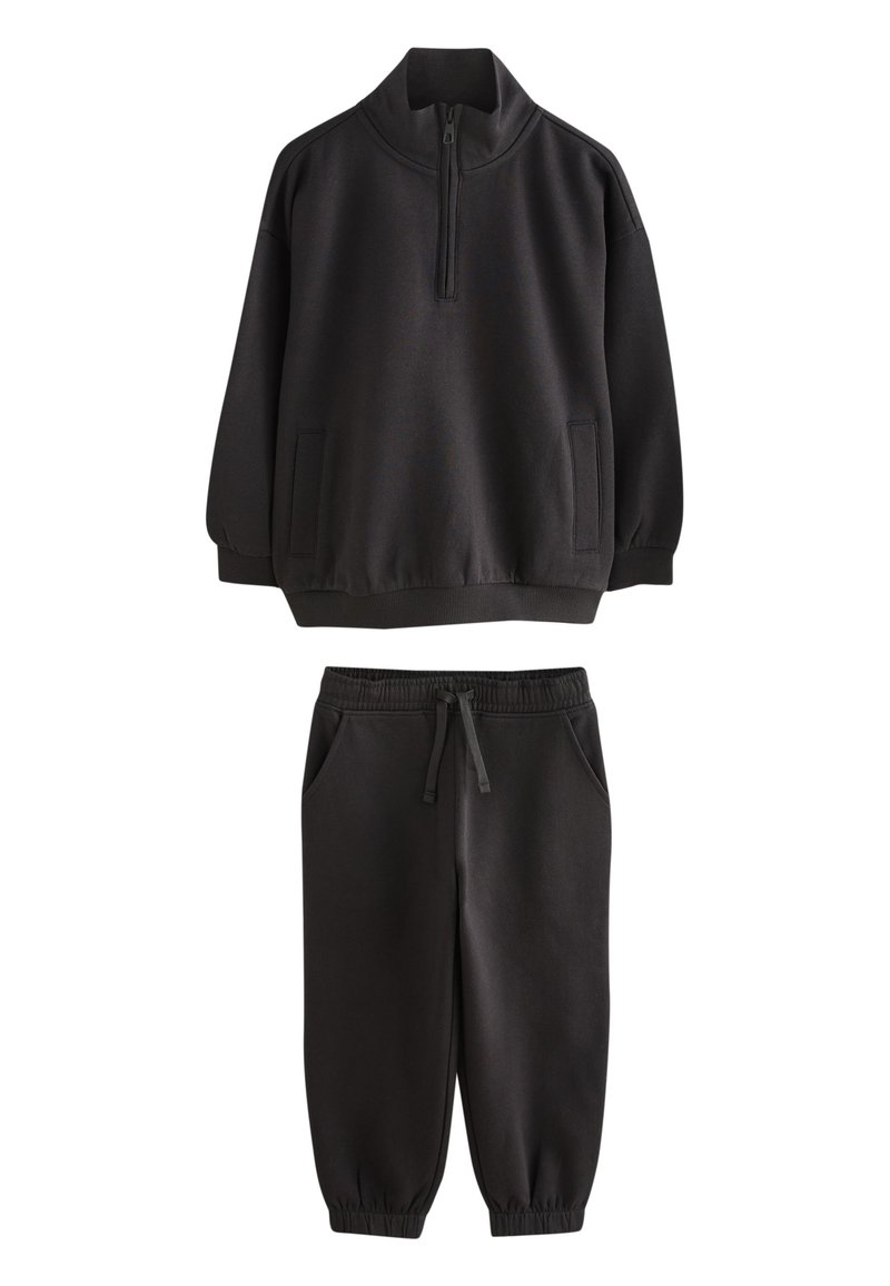 Sweat-shirt noir avec col à demi-fermeture éclair et poches latérales, assorti d'un pantalon de survêtement noir avec taille et poignets élastiques.
