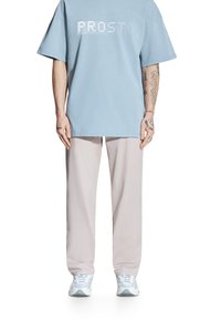 Jasnoniebieska, przezroczysta koszulka z białymi literami z cyrkonii. Połączona z jasnoszarymi spodniami i białymi trampkami. Luźny i wygodny fason.