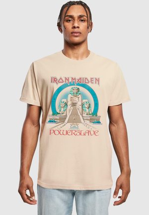 Beige bomulds t-shirt med et Iron Maiden grafik. Designet inkluderer egyptiske motiver og fed rød tekst, der står "Powerslave."
