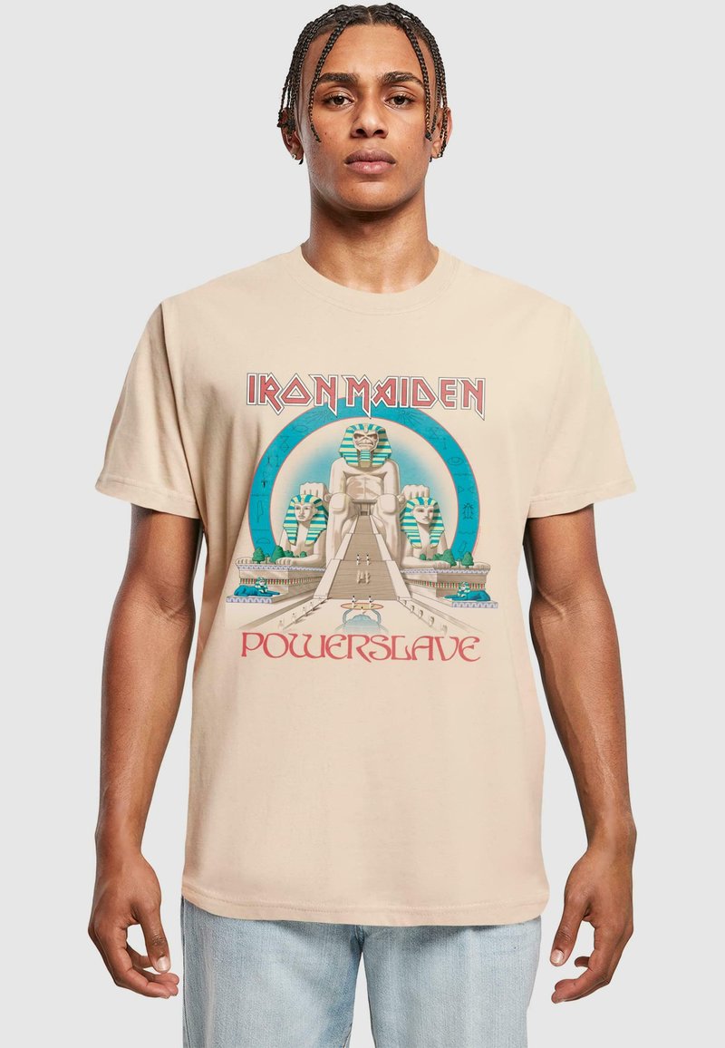 Beige bomull T-skjorte med et Iron Maiden-trykk. Designet inkluderer egyptiske motiver og fet rød tekst som sier "Powerslave."
