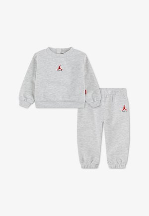 Jasnoszary dres dziecięcy z bluzą z długim rękawem i spodniami dresowymi, oba z małym czerwonym logo Air Jordan na piersi i biodrze.