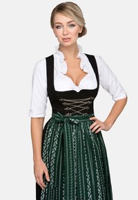 Traditionelles Kleid mit schwarzem Oberteil und grünem, plissiertem Rock mit Blumenmustern. Der Stoff hat eine glatte Textur und ist mit einem Band verziert.