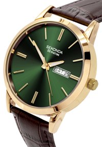 Montre dorée avec un cadran soleillé vert, marqueurs d'heure blancs et affichage de la date. Bracelet en cuir brun avec une texture embossée. Étanche jusqu'à 50 mètres.