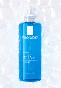 Blue plastic bottle with a pump top, labeled "Lipikar Gel Lavant," featuring white text on a smooth, glossy surface; surrounded by bubbles.