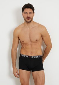 Boxeri negri dintr-un amestec de bumbac, având un talie cu logo-ul Guess în contrast. Textură netedă și design aderent.