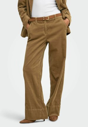 Pantalon large en velours côtelé marron avec ourlets retroussés, porté avec une veste assortie, une ceinture marron, un haut blanc et des escarpins marron à bout pointu.