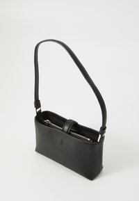 Sac à bandoulière en cuir noir avec fermeture éclair, de forme rectangulaire, corps plat et bandoulière réglable. Présente un design minimaliste avec des accessoires en or.