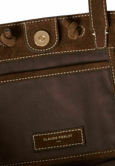 Borsa in suede marrone con chiusura a scatto dorata, cuciture bianche e interno in tessuto. Presenta un'etichetta con la scritta "CLAUDIE PIERLOT PARIS."