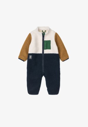 Fleece onesie in cream, brown, and navy. Features a green patch pocket, zip closure, and textured fabric. Cozy design for warmth.