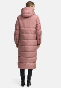 Long, puffer coat in soft pink with a hood, featuring horizontal quilted sections, zippered pockets, and a relaxed fit.