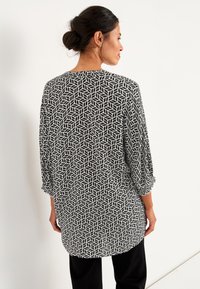 Schwarze und weiße gemusterte Bluse mit einem geometrischen Blattformdesign, Dreiviertelärmeln und einem lässigen Schnitt. Weicher, leichter Stoff.