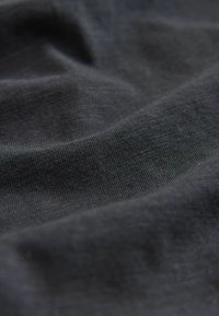 Material textil gri închis cu o suprafață netedă, ușor texturată, având un luciu subtil, prezentând pliuri delicate și o țesătură fină tricotată.