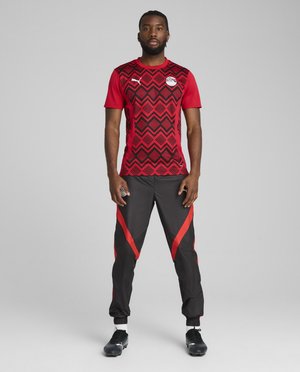 Rød og sort atletisk trøje med et geometrisk mønster, parret med sorte bukser med røde accenter. Glat stof, tætsiddende design.