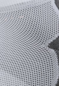 Tissu en maille blanche avec un motif hexagonal et une texture fine ; présente des nuances de gris variées, créant un effet dégradé.