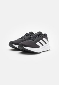 Black athletic shoes with a textured upper, white three-stripe logo, cushioned white midsole, and rubber outsole.