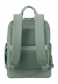 Sac à dos en tissu vert avec un dos en maille rembourrée, des bretelles réglables et une base structurée. Présente des accents ribbed horizontaux à la base.