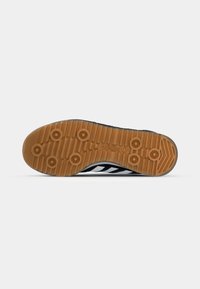 Zwart-witte sport schoen zool met een gestructureerde, rubberen grip in gumkleur, voorzien van cirkelvormige profielpatronen en merktekens.