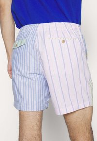 Pantalones cortos a rayas que presentan colores azul claro y rosa con líneas verticales. Cintura elástica con bolsillos abotonados y solapas de bolsillo en contraste.