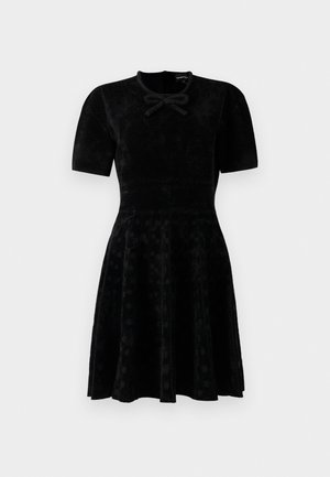 Black short-sleeve velvet dress with fitted waist, flared skirt with subtle polka dots, and a small bow detail at the neckline.