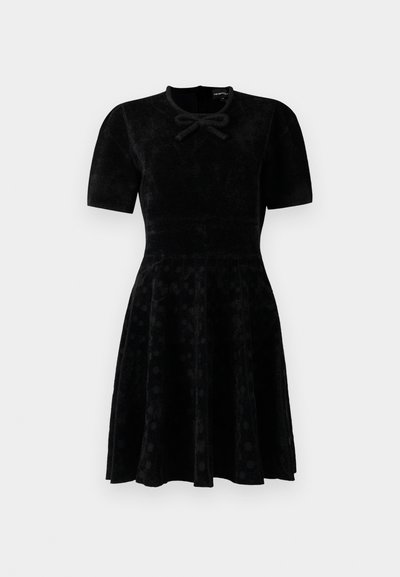 Black short-sleeve velvet dress with fitted waist, flared skirt with subtle polka dots, and a small bow detail at the neckline.