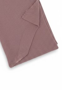 Coperta lavorata a maglia color malva, piegata, con bordo a coste. Il materiale sembra morbido con un motivo a nido d'ape per una maggiore texture.