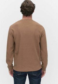 Bruine langermige shirt gemaakt van gestructureerde stof, met een ronde halslijn en een rechte snit, voorzien van een subtiel geribbeld patroon.