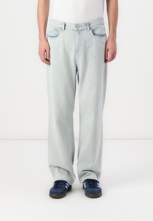 Lyseblå, løstsittende denimjeans med knappelukking, to frontlommer og en jevn tekstur. Kombinert med mørke sneakers.