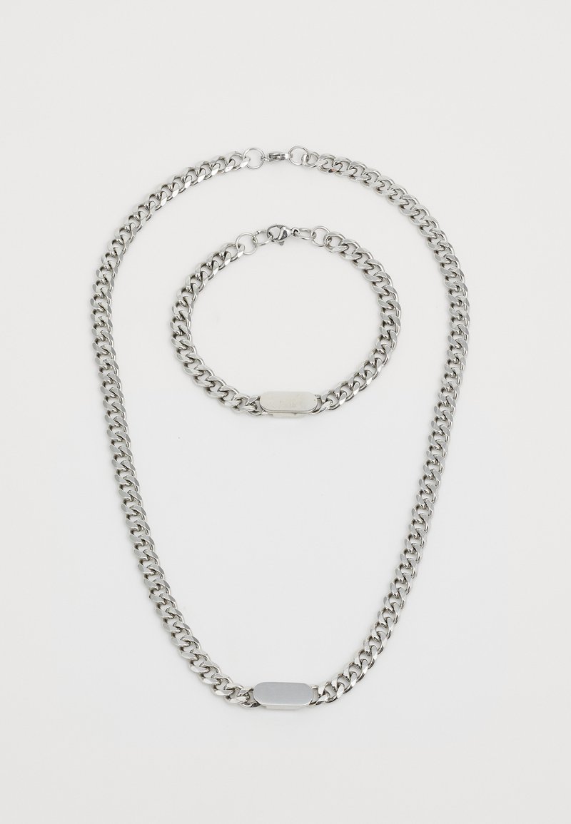 Silver-tone metal chain necklace and matching bracelet with flat rectangular plaques on a white background.
