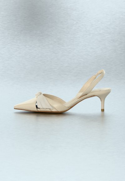 Παιδικό παπούτσι με μπεζ δερμάτινο λουράκι στο πίσω μέρος, ψηλό τακούνι στιλέτο με αιχμηρή μύτη και διακοσμητικό κόμπο στην κορυφή.