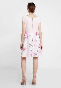 Un vestito floreale rosa con un corpetto aderente, maniche corte e una gonna svasata, adornato con motivi floreali in stile acquerello.