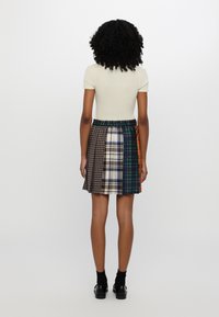 Falda de cuadros multicolor con cintura elástica, que presenta varios patrones incluyendo pata de gallo y cuadros, diseño hasta la rodilla.