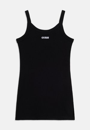 Crna rebrasta majica bez rukava s tankim naramenicama i bijelim "GUESS" logom smještenim u sredini ispod izreza.
