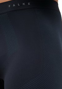 Leggings FALKE noirs avec un design texturé, ornés de rayures diagonales bleu foncé et d'une taille renforcée pour un ajustement et un confort améliorés.