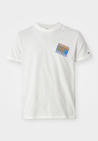 White short-sleeve t-shirt with a blue and orange "Tommy Jeans" logo on the left chest and a small flag emblem on the left sleeve.